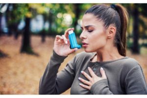 Kobieta z inhalatorem po narażeniu na czynniki wyzwalające napady astmy